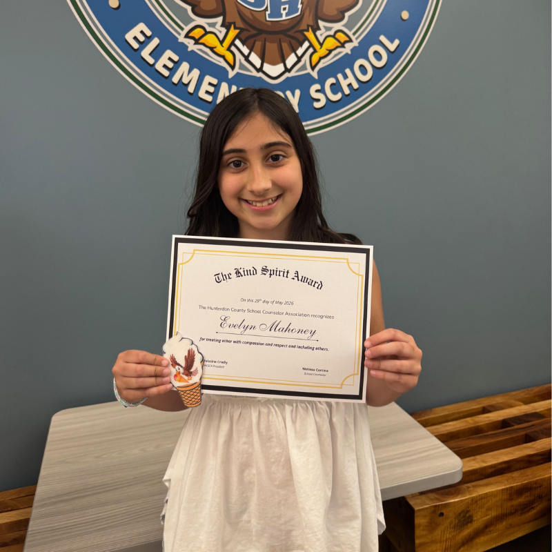 A smiling girl holds a certificate for the "Kind Spirit Award" from Hunterdon County School Counselor Association.