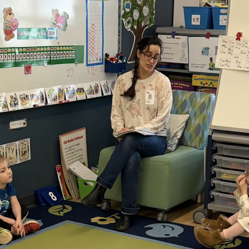 A presenter sits in a chair. 