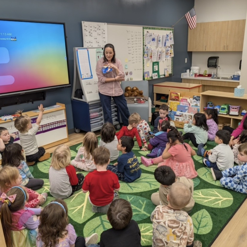 A teacher stands in front of a group of children. 
