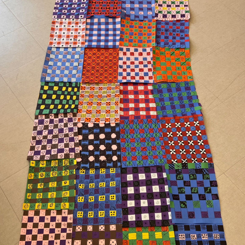 A colorful woven art project featuring many squares with diverse patterns and designs.