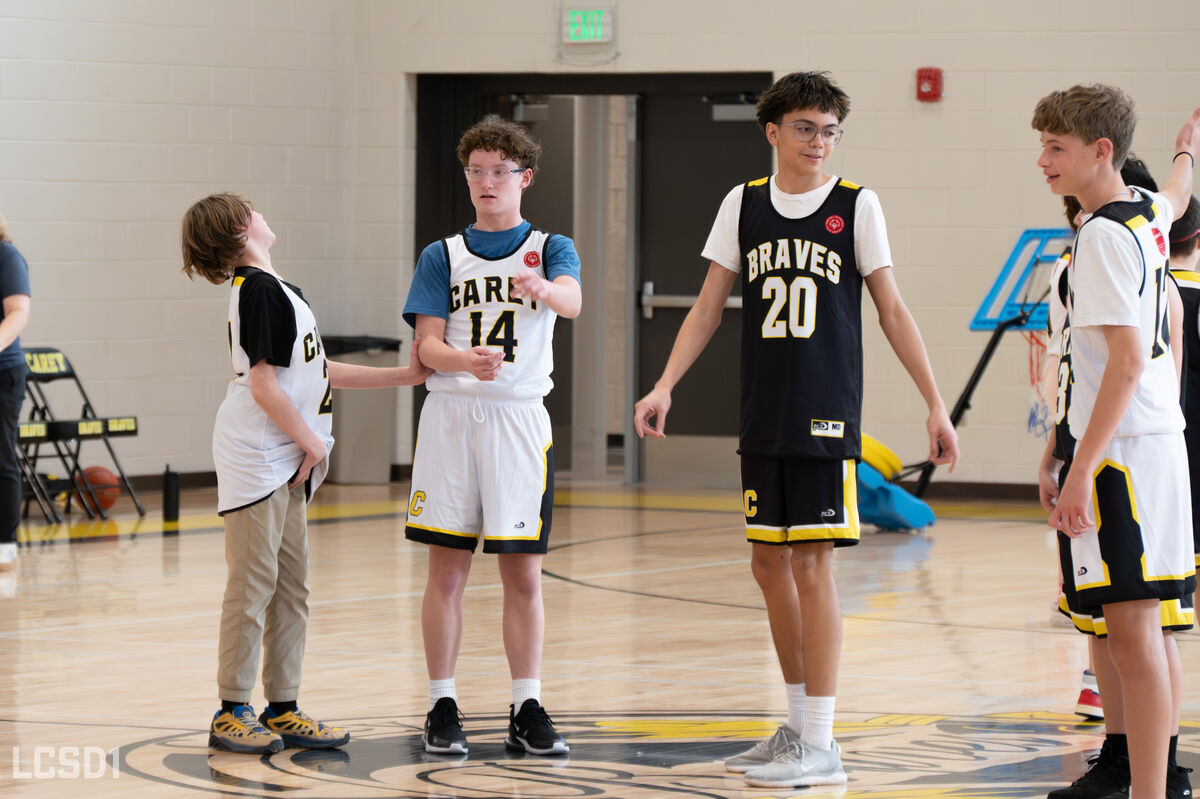 Students in basketball uniforms talk to each other.