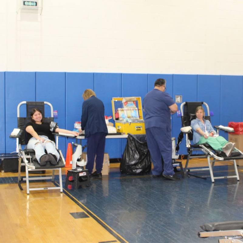 A blood drive is underway with donors reclining in chairs while medical staff attend to them.