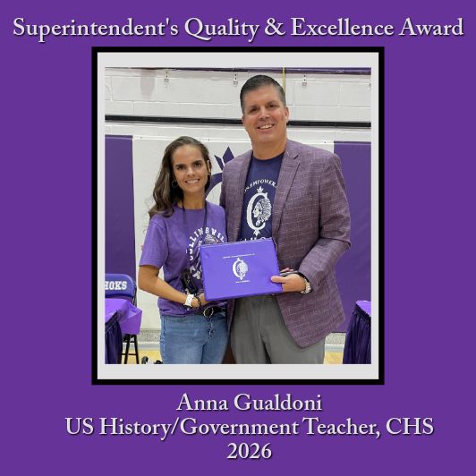 A man in a suit and a woman in a purple shirt smile while holding a purple award certificate.