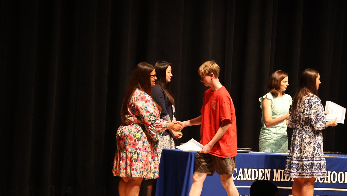 An eighth grade student receives their certificate