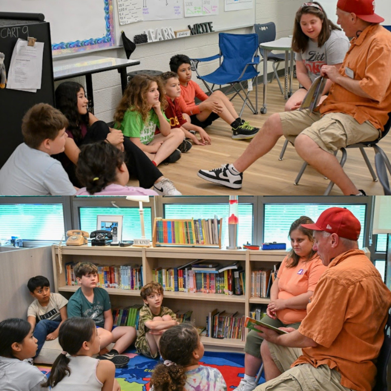 A man reads a book to a group of children sitting on the floor in a classroom.