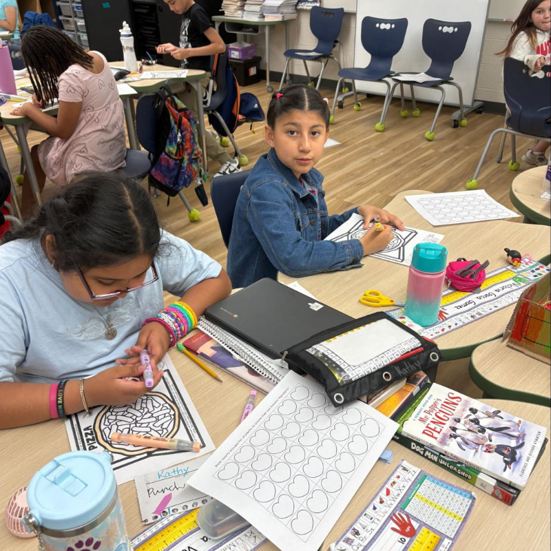 Students are engaged in an art activity at their desks, coloring and drawing.