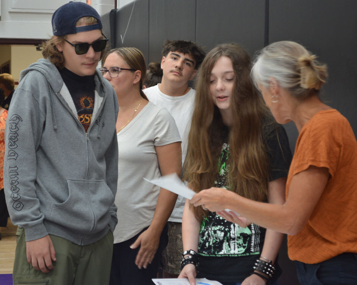 A woman shows papers to a student and an adult.