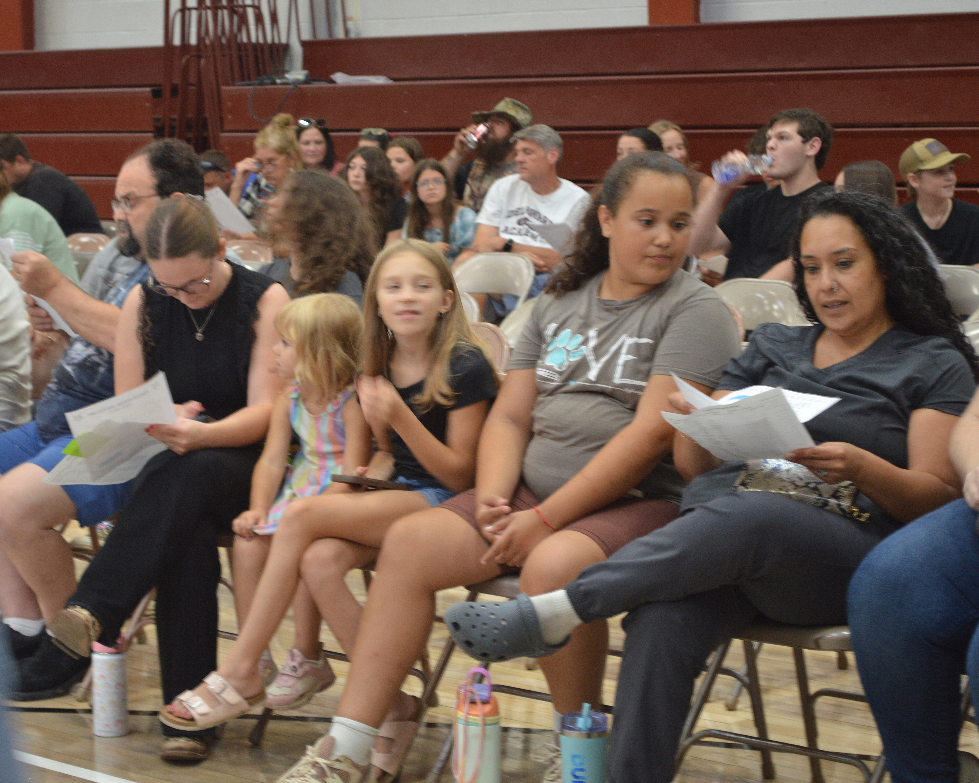Adults look at papers as students sit between them.