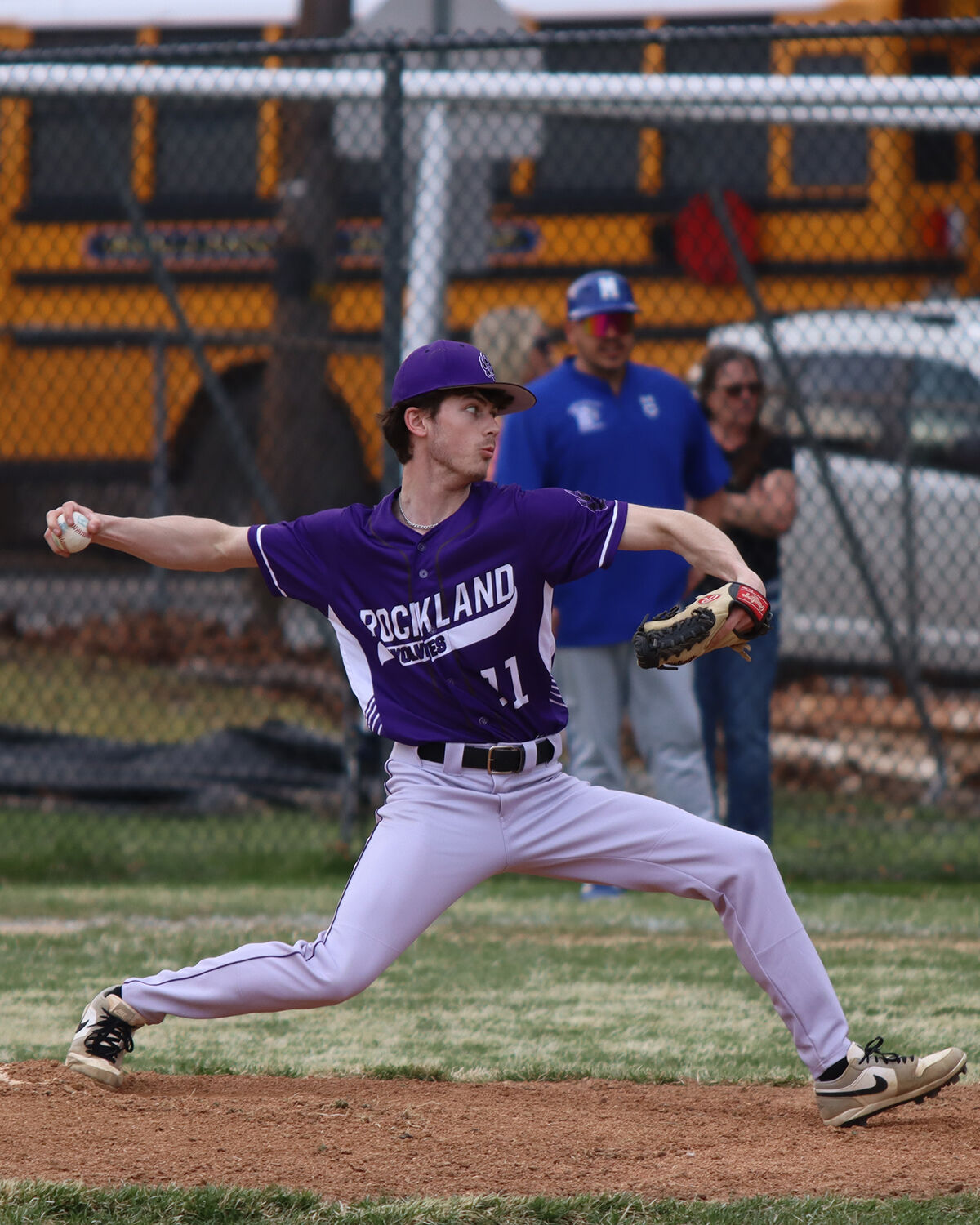 A baseball pitcher in a purple uniform with 'ROCKLAND WOLVES' on it throws a pitch.