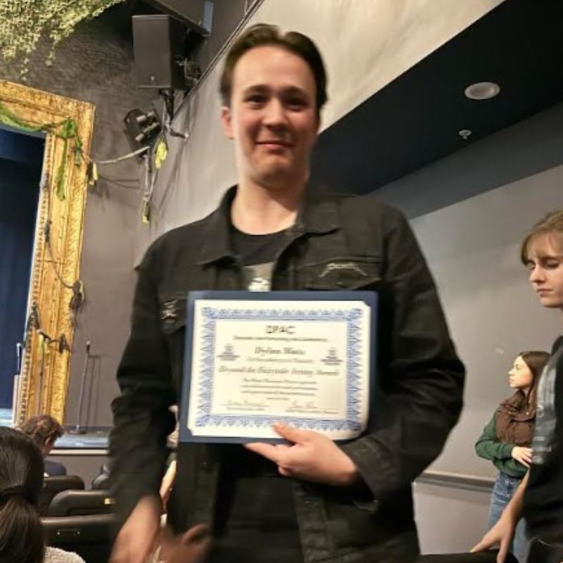 A young man proudly holds a certificate from DPAC, awarded for "Beyond the Barricade Acting Award."