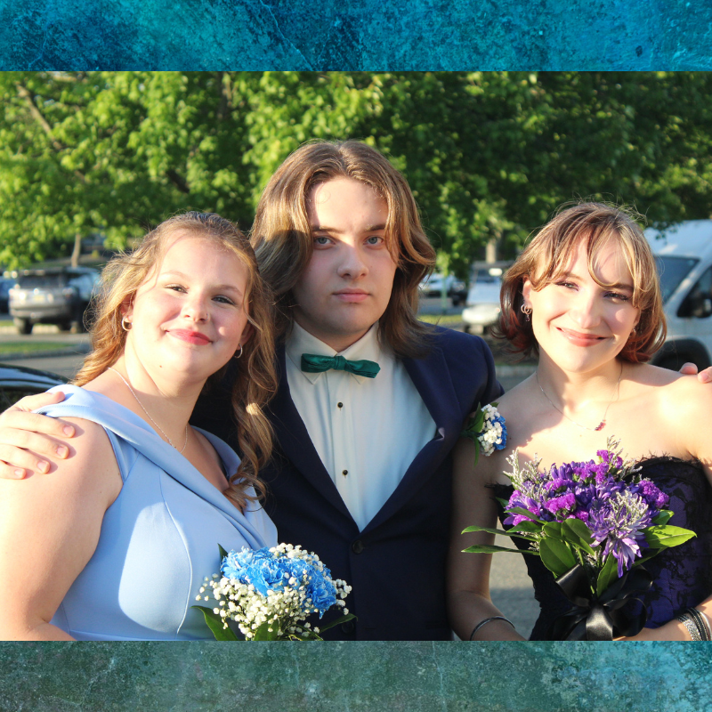 Three young people in formal attire pose for a photo, holding bouquets.