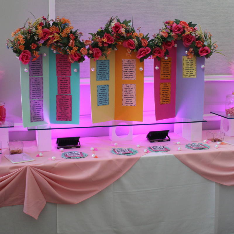 A table display features colorful seating charts adorned with floral arrangements.