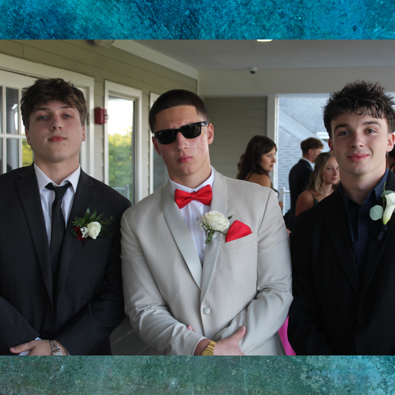Three young men in formal attire pose for a photo, dressed for a special occasion.