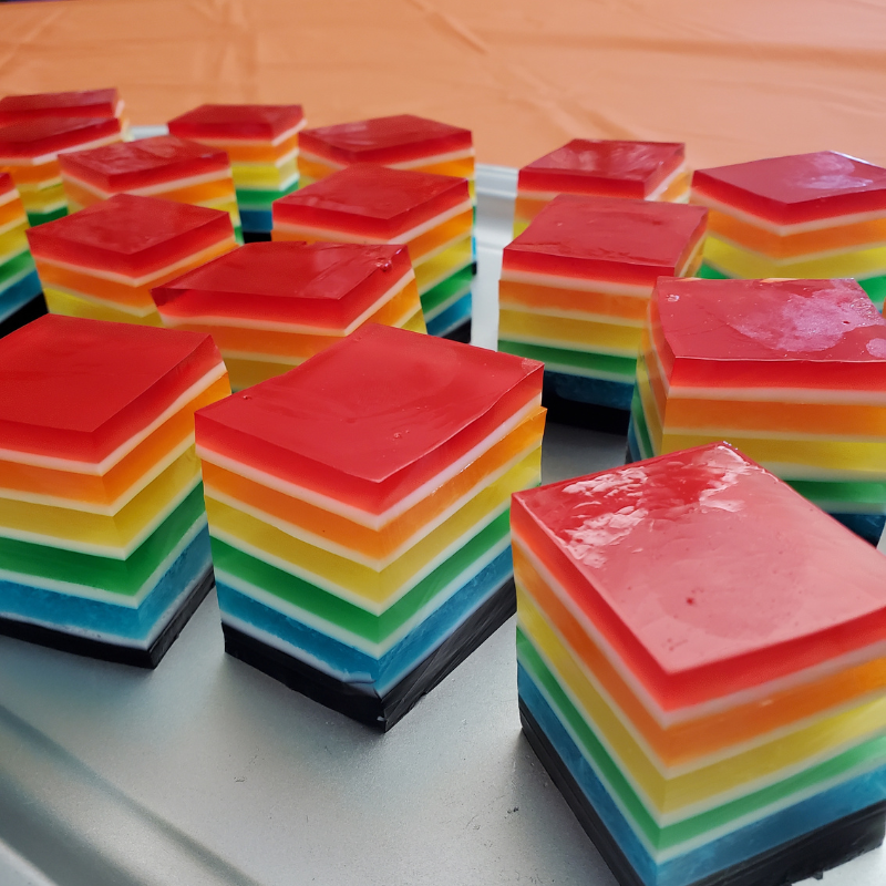 A tray of colorful layered jelly cubes arranged in rows.