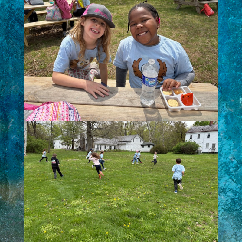 Two smiling children sit at a picnic table with a lunch tray and water bottle.