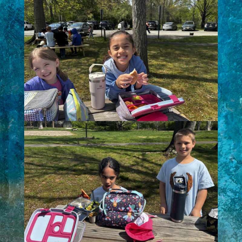 Four children enjoy a picnic lunch outdoors at a wooden table with lunchboxes and drinks.