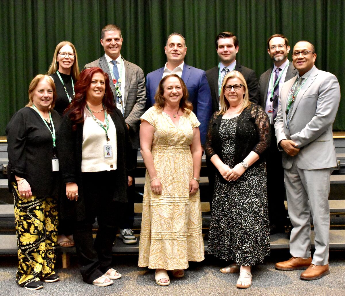 A group of ten people, dressed in professional attire, stand together posing for a photo.