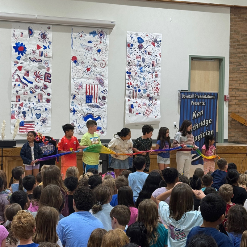 Children hold a colorful fabric as part of a magic show presented by Ken Northridge.