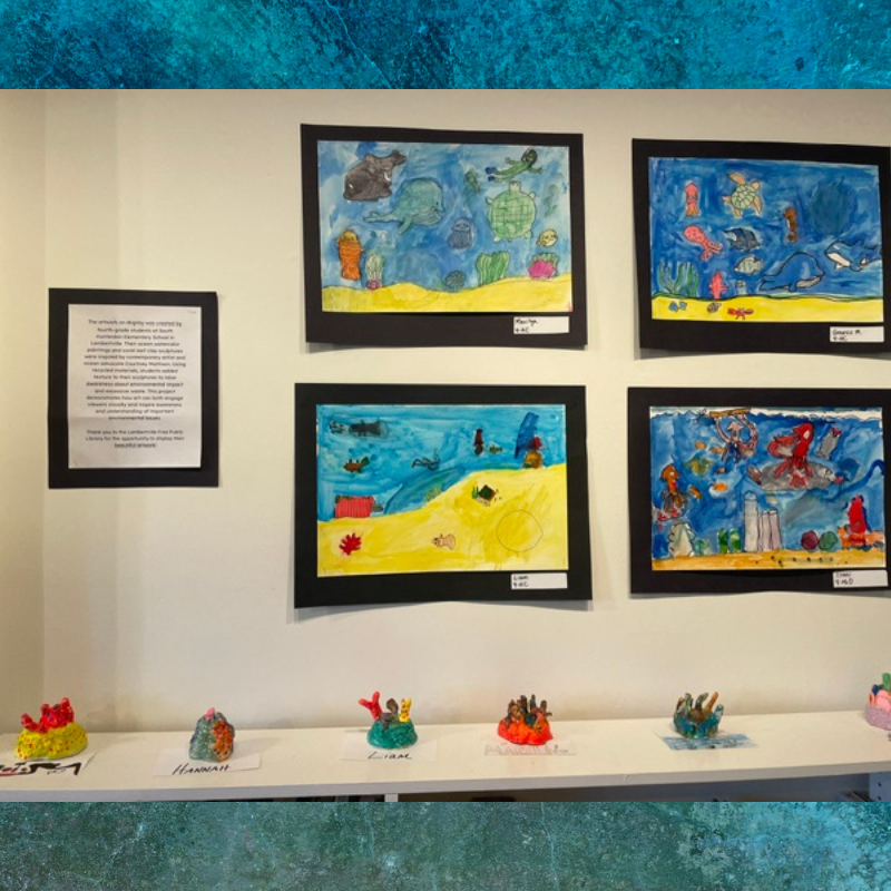 A wall displays children's artwork featuring underwater scenes with marine life and coral sculptures below.