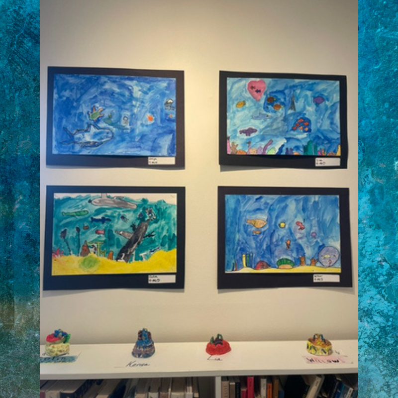 Four framed watercolor paintings of underwater scenes hang on a white wall.