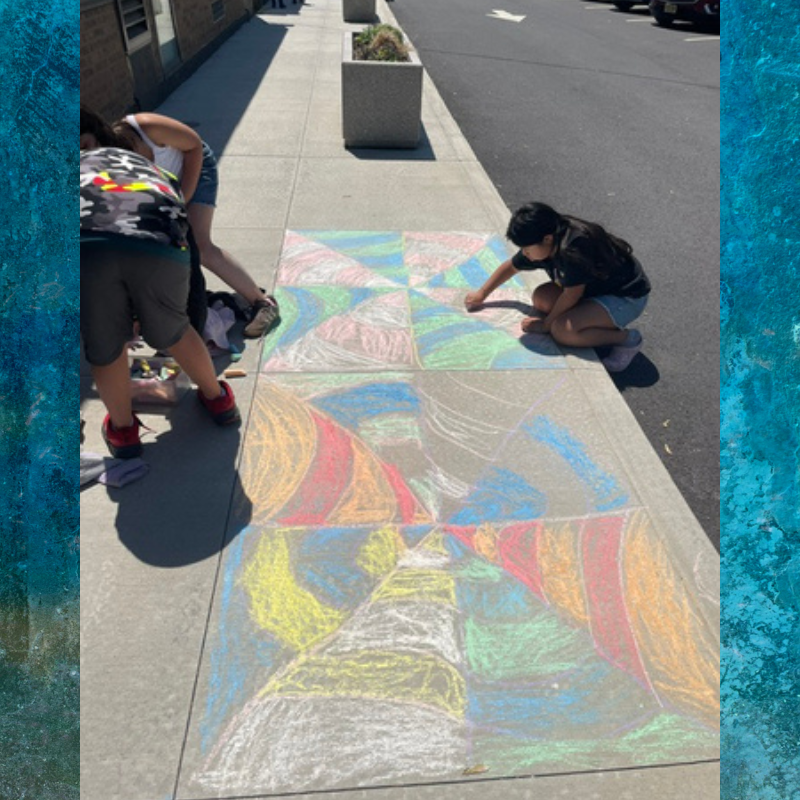 Children create colorful chalk art on a sidewalk, filling geometric patterns with vibrant hues.
