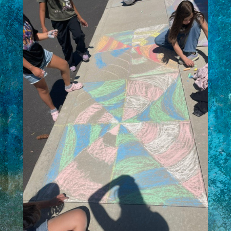 Children create a colorful chalk art design on a sidewalk.