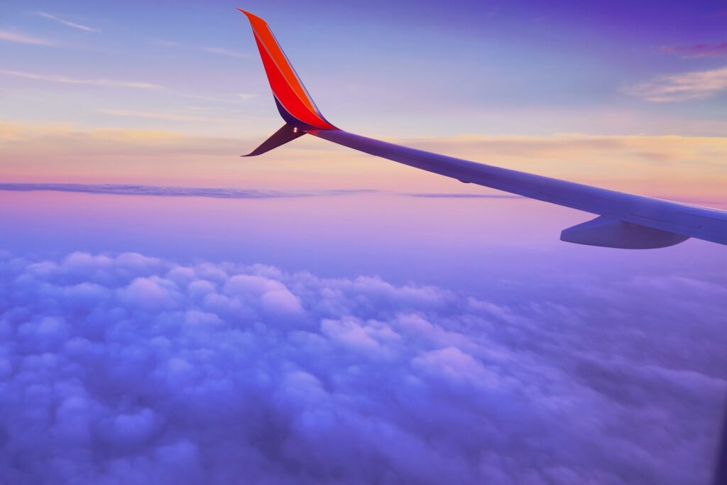 The wing of a plane over sunset clouds