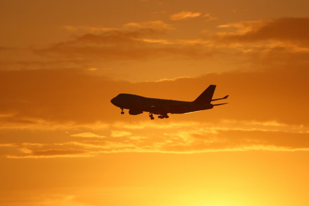 A plane flying across a golden sunset sky