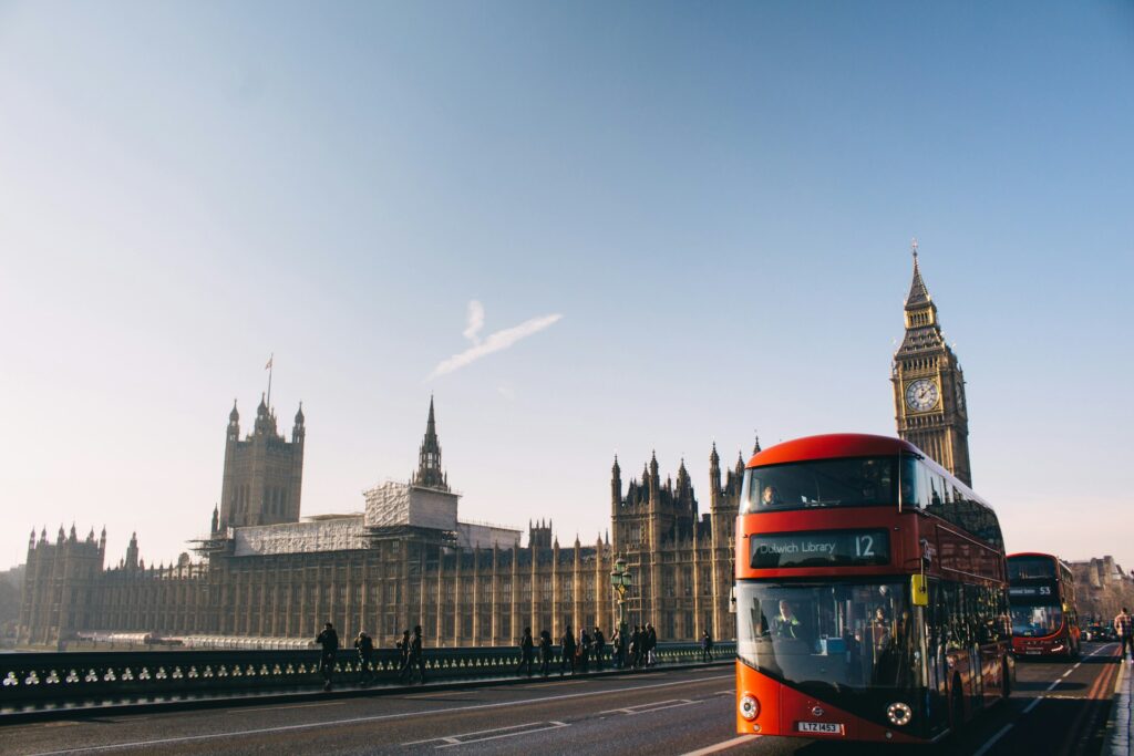 A red bus and in front of the Houses of Parliament