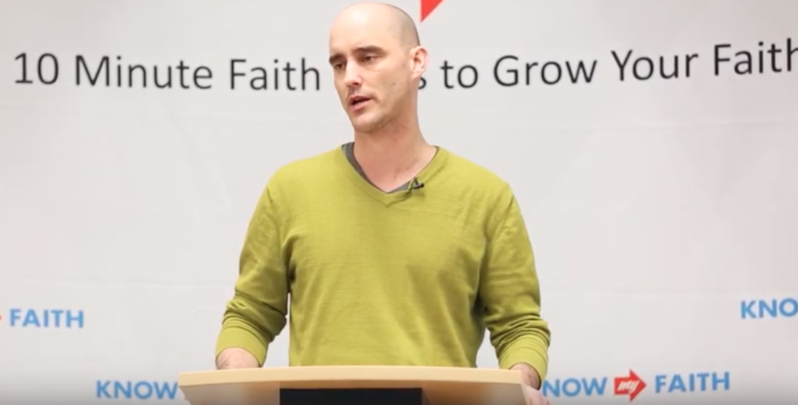 Image of Kevin Timpe giving a presentation wearing a green sweater