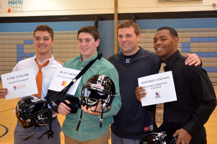 SM East football players Luke Taylor, Ryan Carter and Dominique Atkinson were congratulated by coach Dustin Delaney on their signing to plan college football.