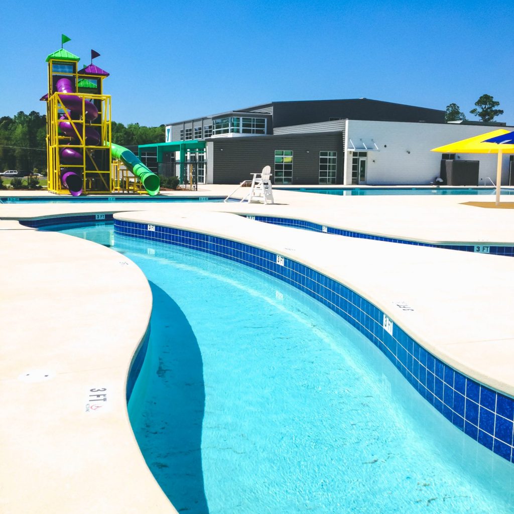 Image of a blue lazy river swimming pool with double water slide in the background.