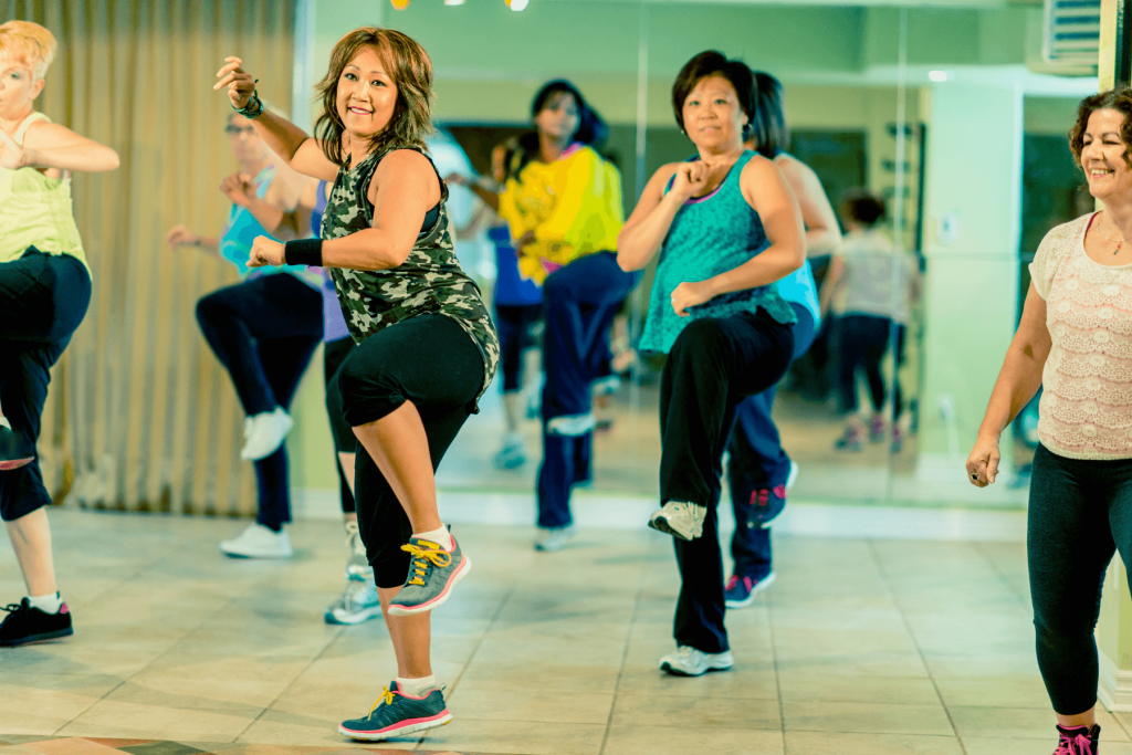a group of ladies perform a kick move in their fitness class.