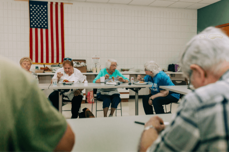 4 senior adults sitting at a table enjoying food and conversation with each other.