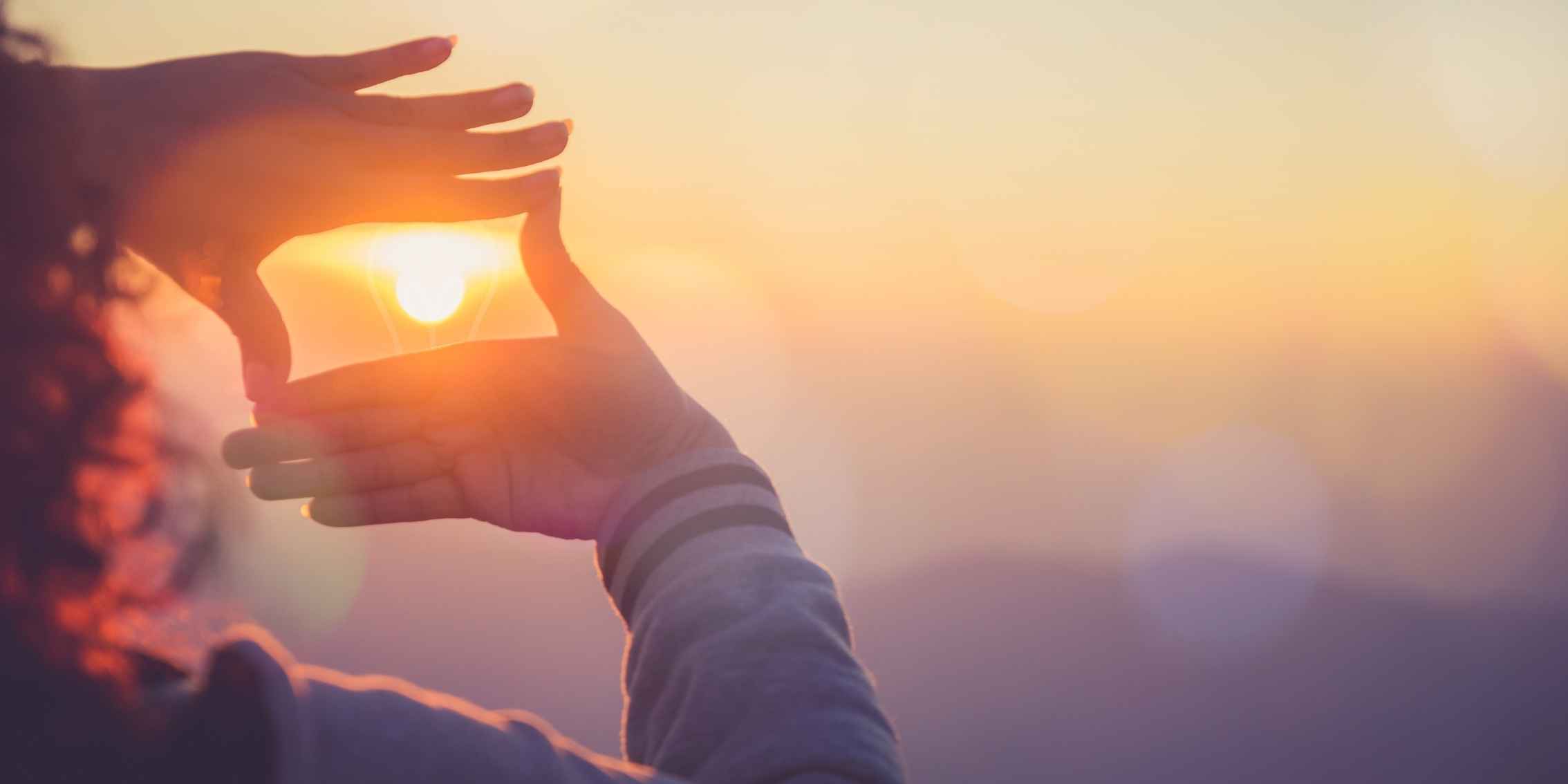 Women framing a sunset between her two hands Women framing a sunset between her two hands