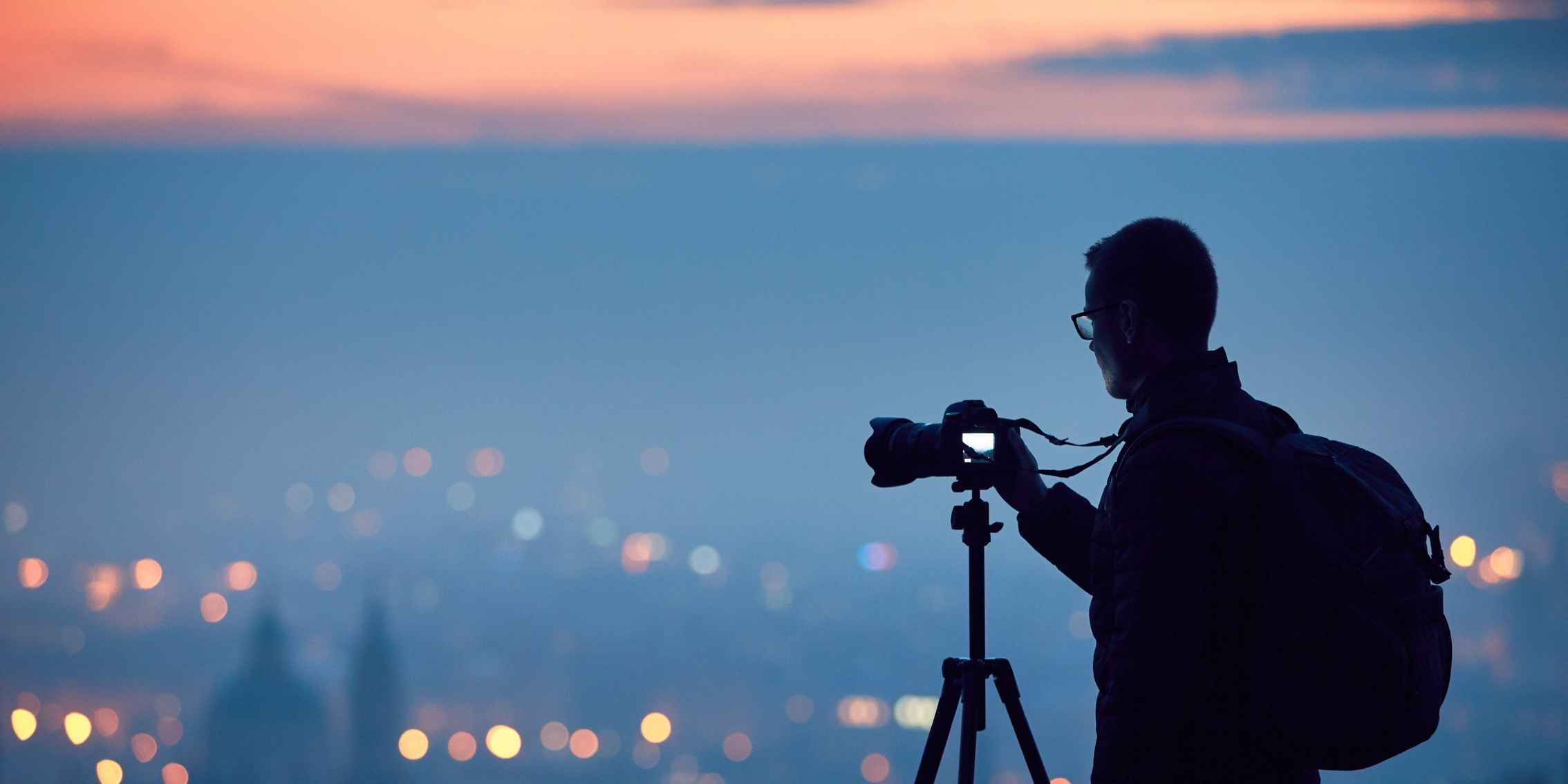 Silhouette of man photographing a cityscape Silhouette of man photographing a cityscape