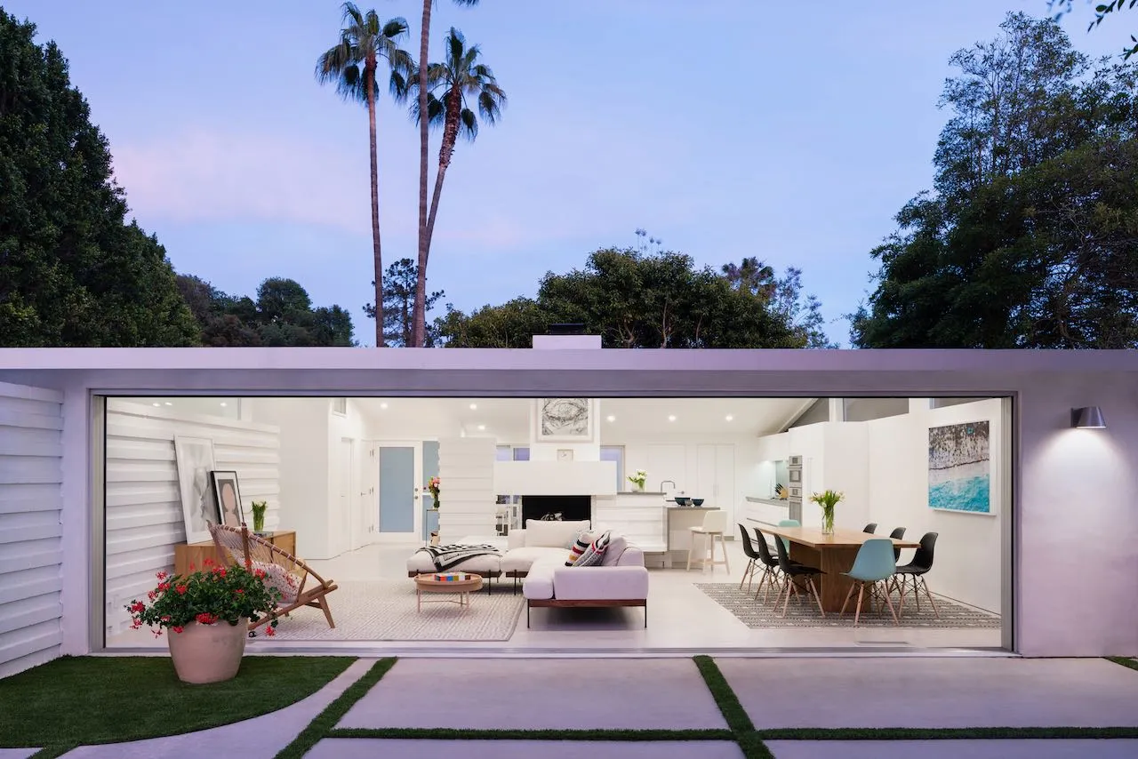 A room completely open to the outside with couch, dinner table, and fireplace.