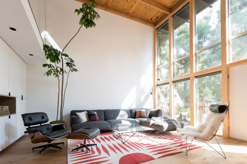 Living room with large windows, a couch, two chairs and a coffee table.