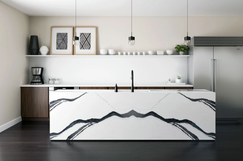 Modern black and white zebra pattern kitchen island in front of a white and dark wood kitchen and large stainless steel refrigerator.