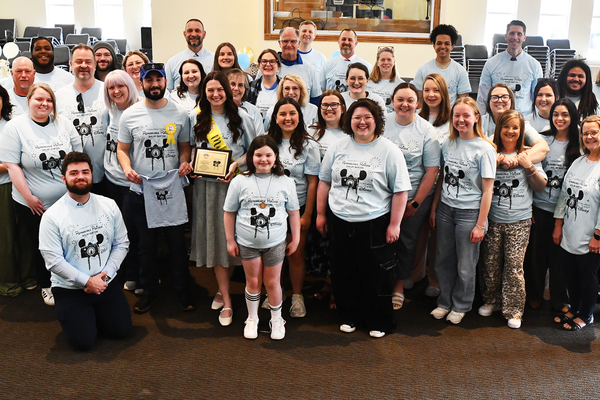 Lindsey Wilson University Assistant Director of Public Relations and Media Producer Shelby Burton, center (holding plaque), is joined by family members, co-workers and students on Friday, March 20, in the Doug and Betty Jean Moseley Auditorium of the Norma and Glen Hodge Center for Discipleship after being named the 2026 Remarkable Raider by the Lindsey Wilson Student Government Association.  