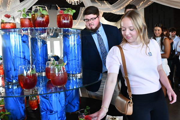 Lindsey Wilson University students Seth Ousley ’26 of Lancaster, Kentucky, and Whitley Gibson ’27 of Edmonton, Kentucky, reach for a mocktail during the Lindsey Wilson School of Business and Communication business dinner etiquette event, held Tuesday, March 31, at Swan’s Landing in Taylor County, Kentucky.