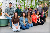 A group of students poses for a photo in a campus greenhouse.