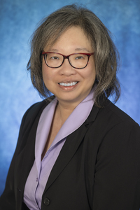 A studio portrait with a blue background of retired SUNY Canton faculty member Christina Lesyk.