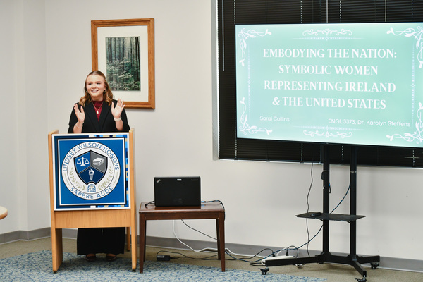 Lindsey Wilson University student Sarai Collins ’28, a women and gender studies and human services and counseling double major from Columbia, Kentucky, presents her research, “Embodying the Nation: Symbolic Women Representing Ireland and the United States,” at the 2026 spring symposium of the R.V. Bennett Honors Program, held Tuesday, April 14, in the Thomas D. Clark Reading Room of the Holloway Building. Collins explored the marginalization of women in Irish and American national identities.
