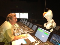 A man at a mixing board looks at a plush version of Olaf from the Disney movie "Frozen."