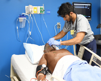 A Dalton State College respiratory therapy student placing an oxygen mask on a manikin in a hospital bed in the college's simulation lab. 