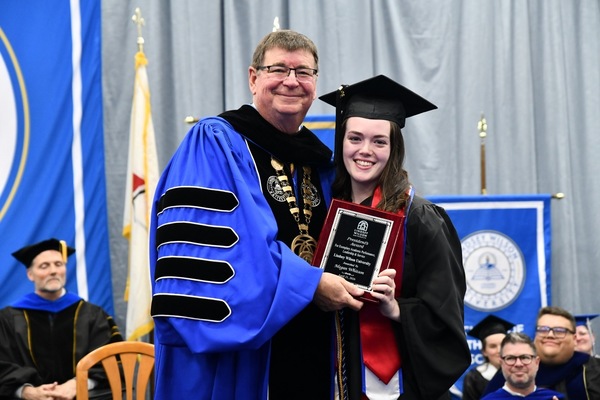 Lindsey Wilson University President William T. Luckey Jr. presents the 2025-26 President’s Award to Megan Whitson '26, an English and communication double major from Bernstadt, Kentucky, at the university's annual Honors Convocation, held Tuesday, April 21, at Biggers Sports Center.