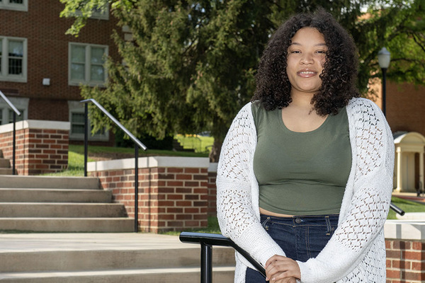 Nia stands on the stairs in front of Ross Hall with her hands on the railing.