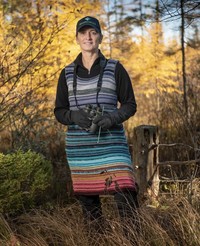 Michale Glennon stands with binoculars outdoors in the woods.