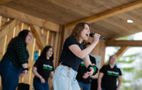 A performer sings into a microphone surrounded by other singers at the Marshall Park bandshell.
